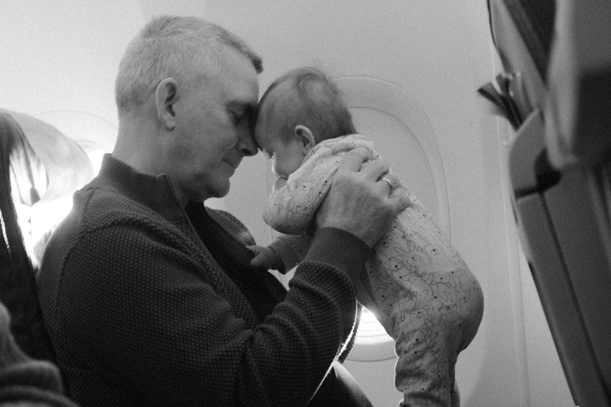 A parent holding a baby on their lap in an airplane seat