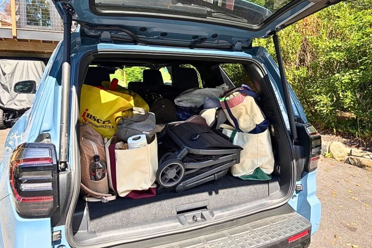 A folded travel stroller packed into an SUV trunk alongside bags